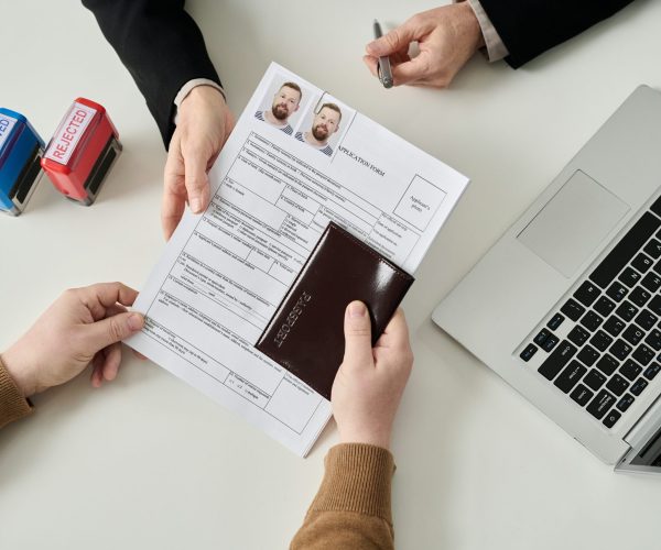 Man applying for visa in immigration office Top view of unrecognizable man applying for visa in immigration office and handing documents to worker